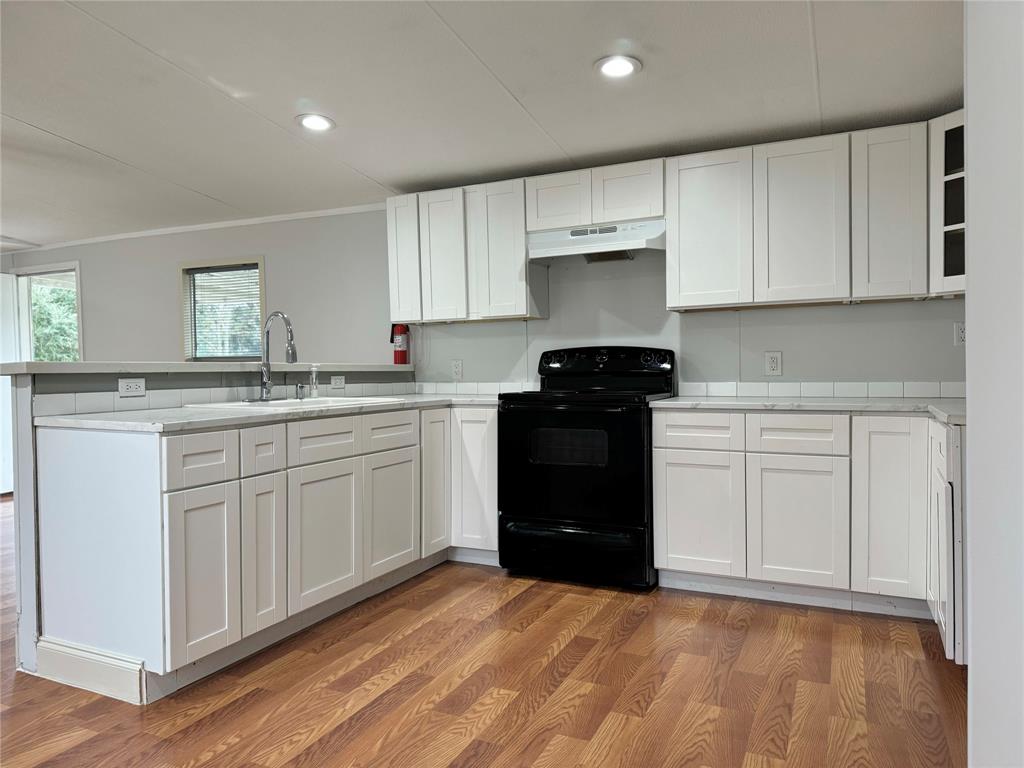 a kitchen with a sink dishwasher a stove and white cabinets