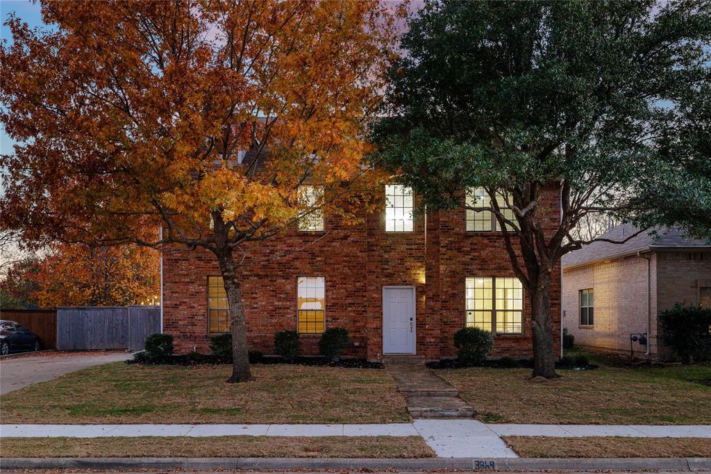 a view of a brick house next to a yard with large trees