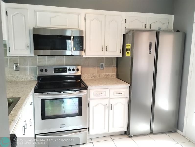 a kitchen with stainless steel appliances white cabinets a stove and a refrigerator