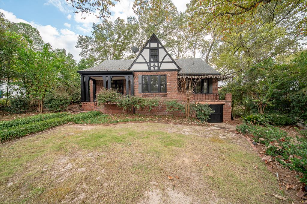 a front view of house with yard and trees in the background