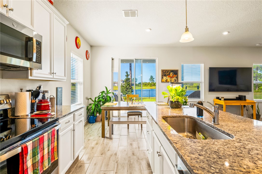 a kitchen with stainless steel appliances a sink a stove and a flat screen tv