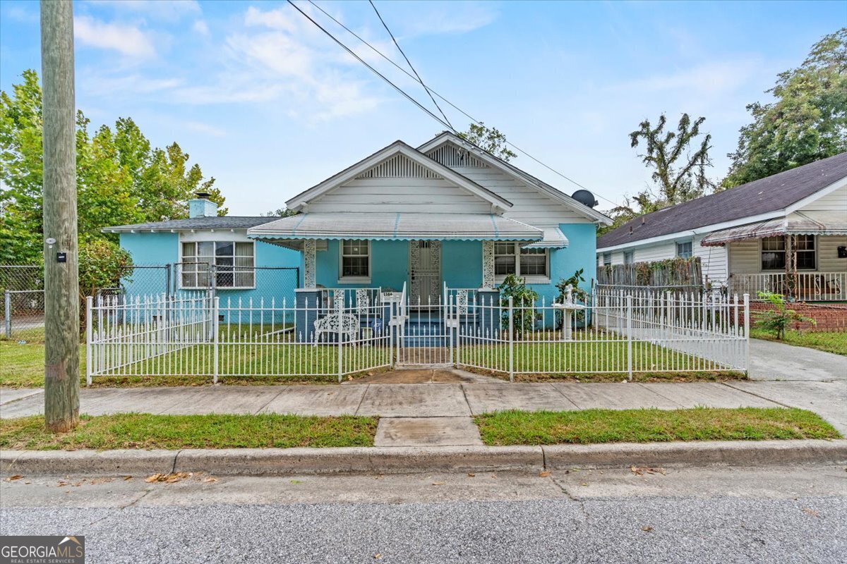 a view of house with a small yard and wooden fence