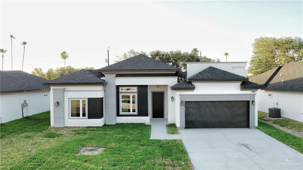 View of front of property featuring central AC unit, a garage, and a front lawn