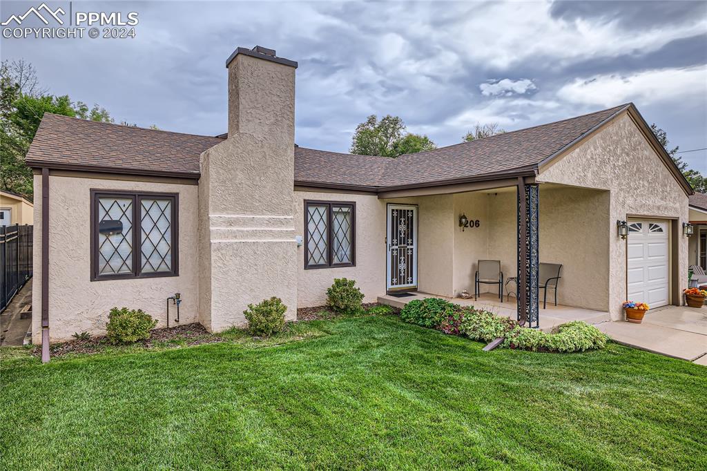 Front of the home with stucco exterior and well cared for front lawn with auto sprinklers.