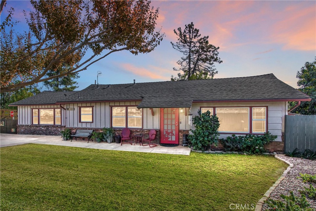 a backyard of a house with table and chairs plants and large tree