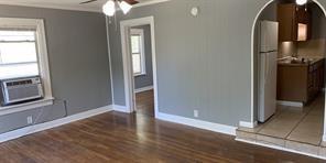 an empty room with wooden floor cabinet and windows