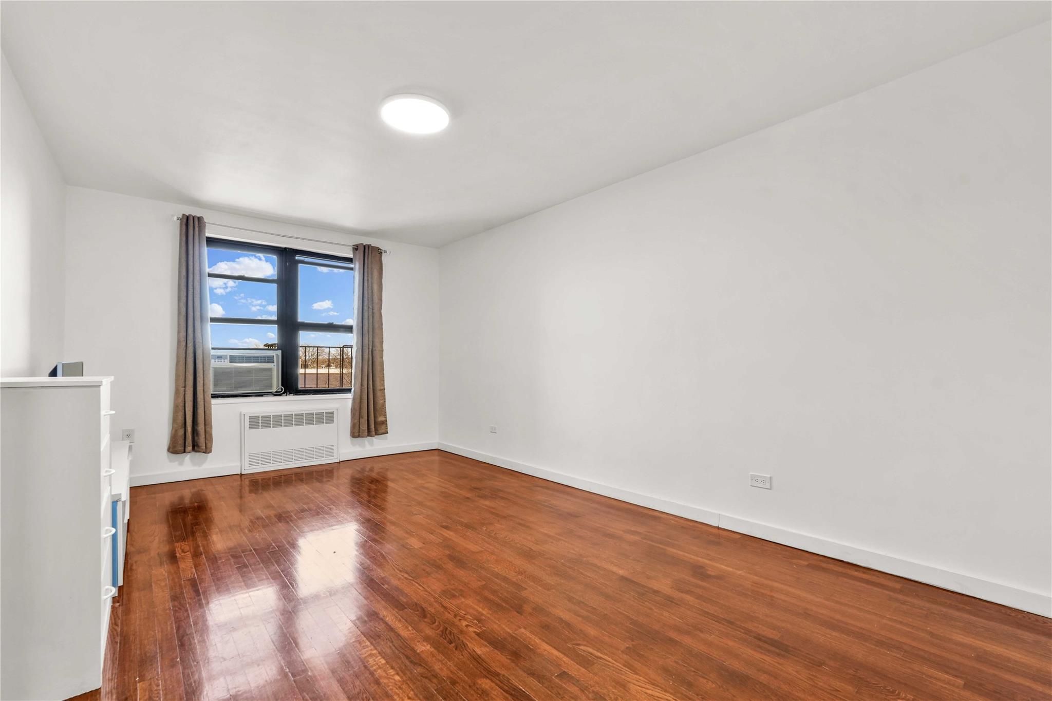 Empty room with radiator heating unit, cooling unit, and wood-type flooring