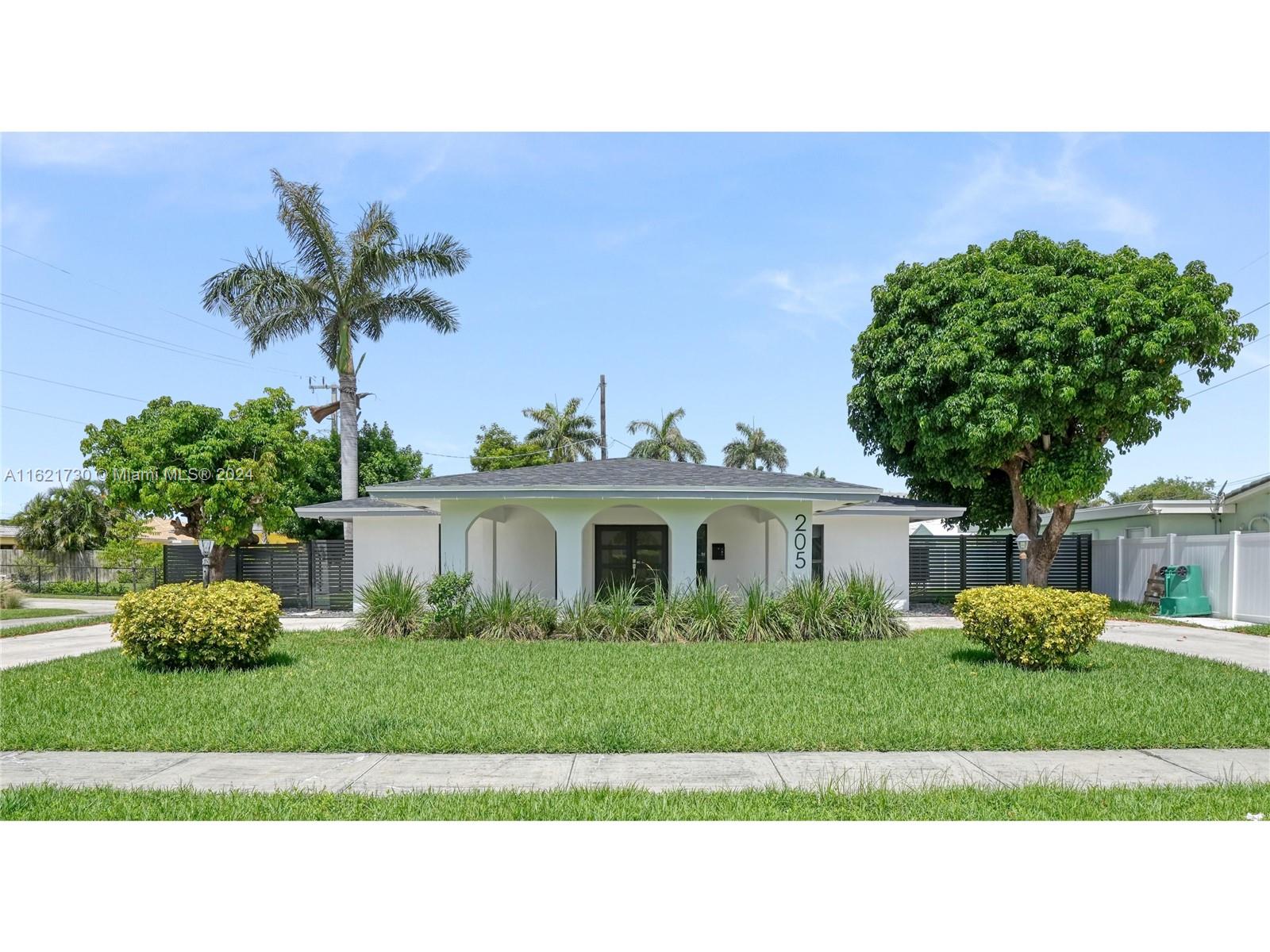 a black white and white house with a big yard and potted plants in front of a house