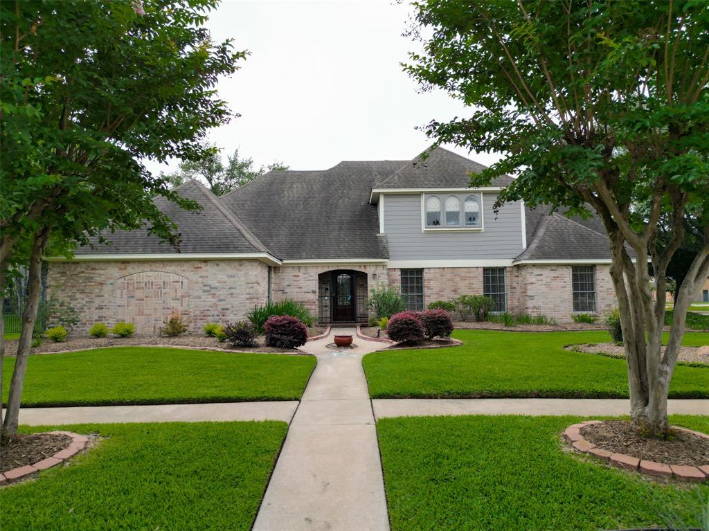 This lovely home presents a picturesque frontage, featuring a well-manicured lawn bordered by vibrant plants. A quaint porch adorned with a graceful archway invites you to step inside and discover the beauty within.