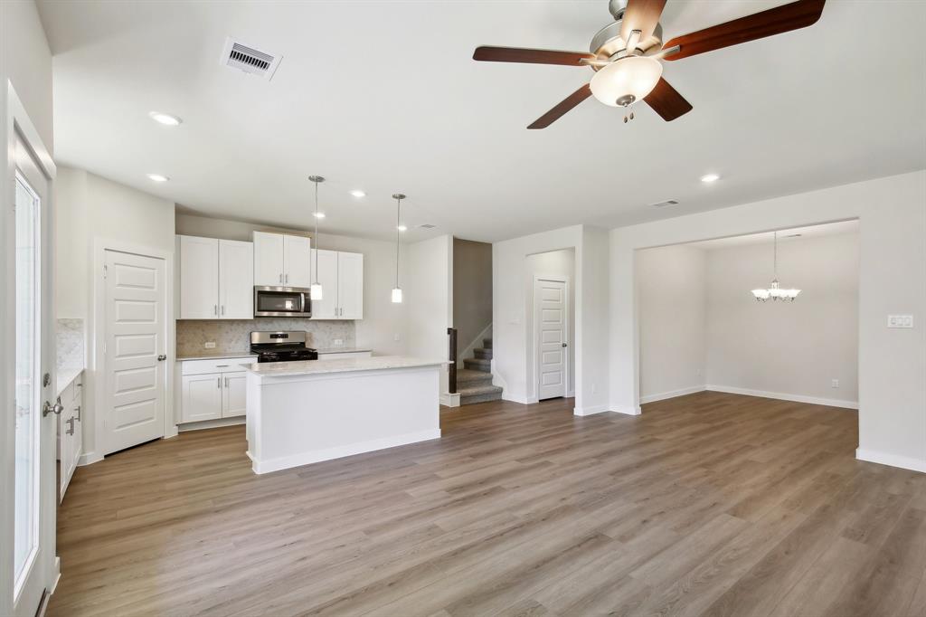 a view of kitchen with stainless steel appliances kitchen island hardwood floor and a sink