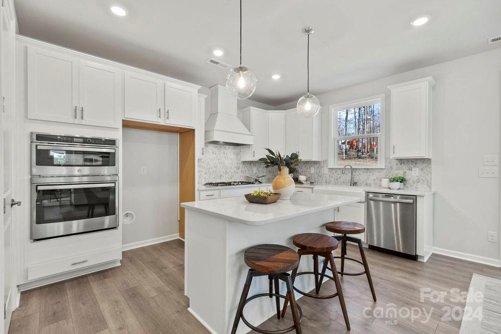 a kitchen with stainless steel appliances a dining table chairs stove and white cabinets