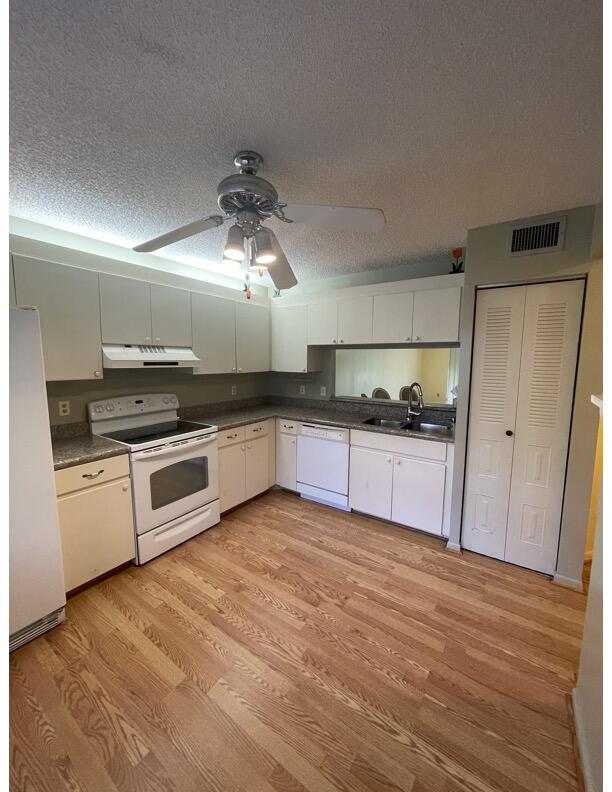 a kitchen with granite countertop a refrigerator and a stove top oven