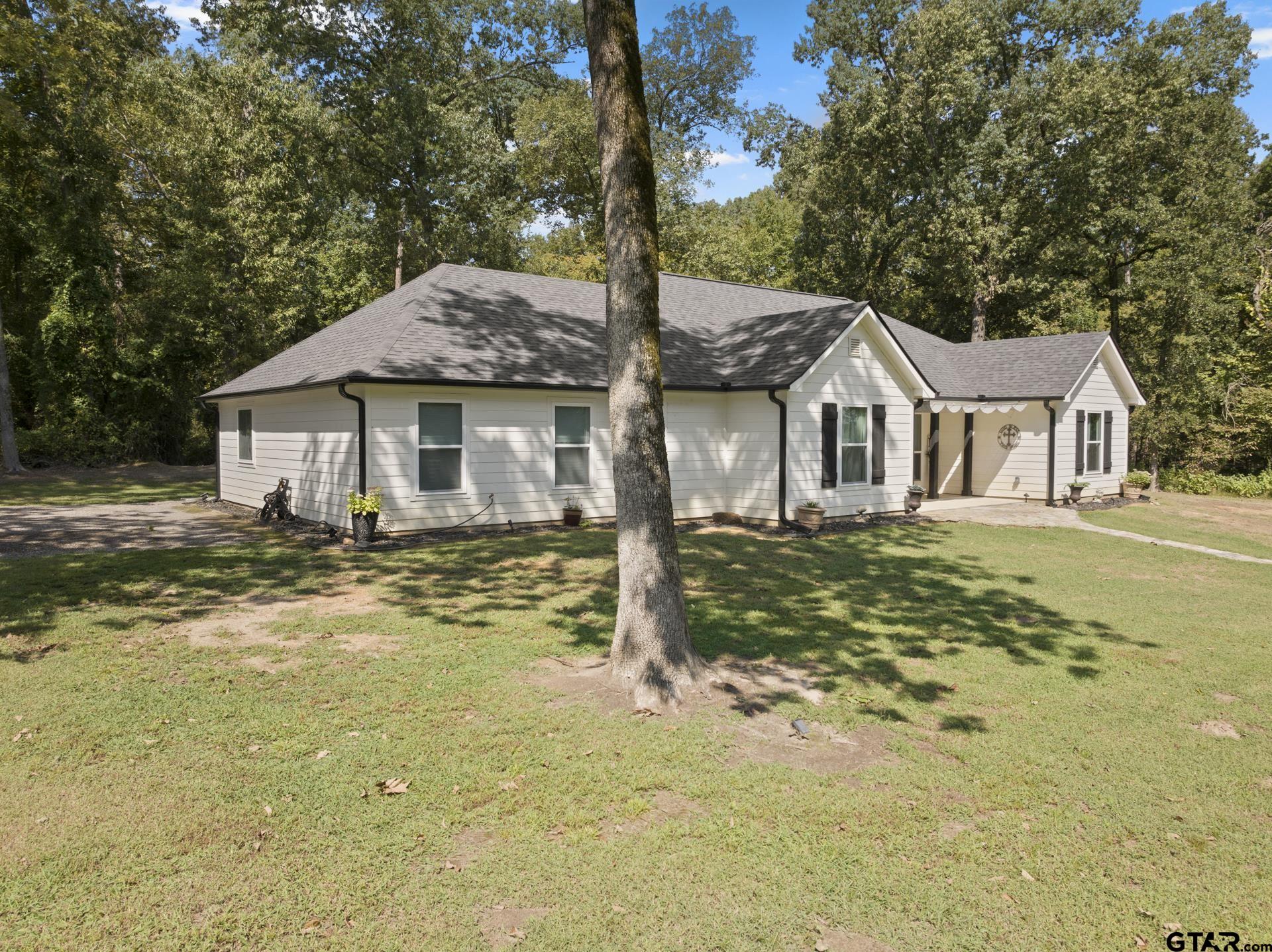 a front view of a house with a garden and tree