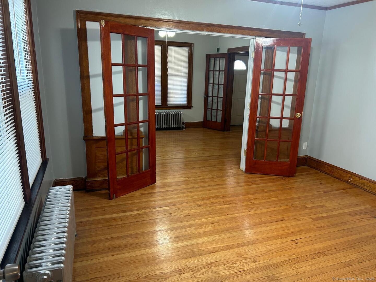 a view of an empty room with wooden floor and a window