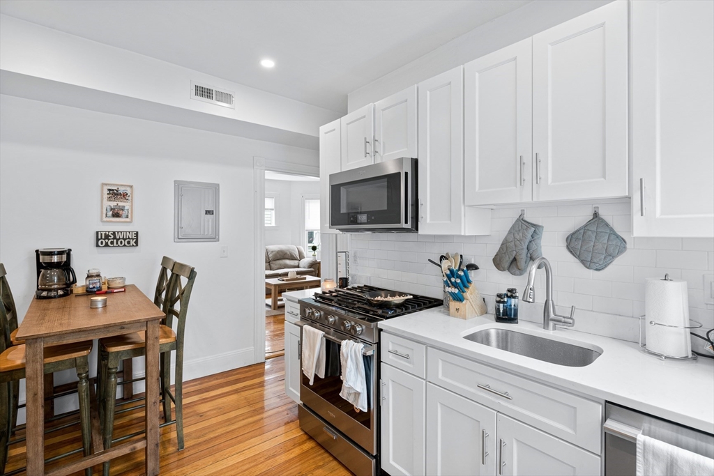 a kitchen with granite countertop a sink a stove a dining table and chairs