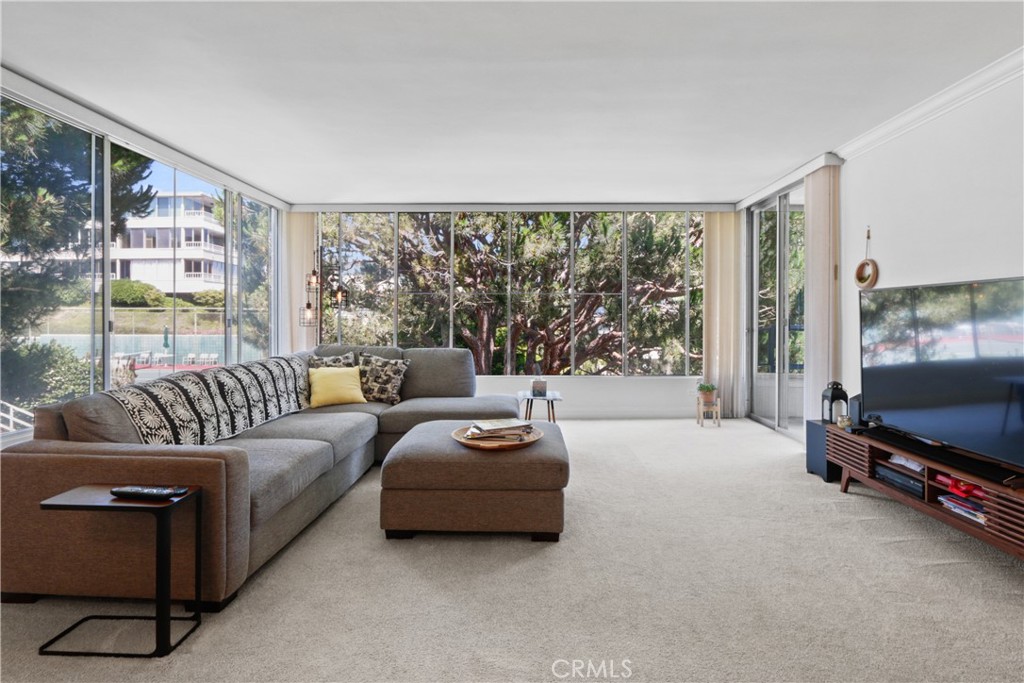 a living room with furniture a flat screen tv and a floor to ceiling window