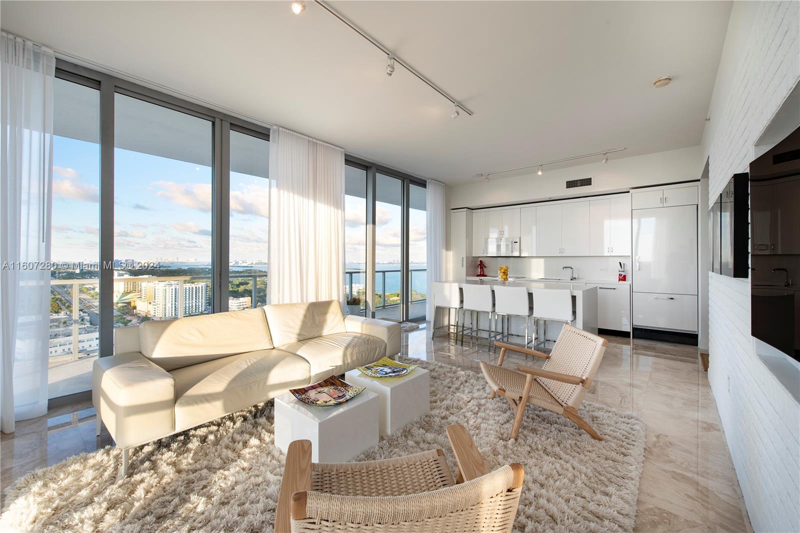 a living room with furniture and a large window with kitchen view