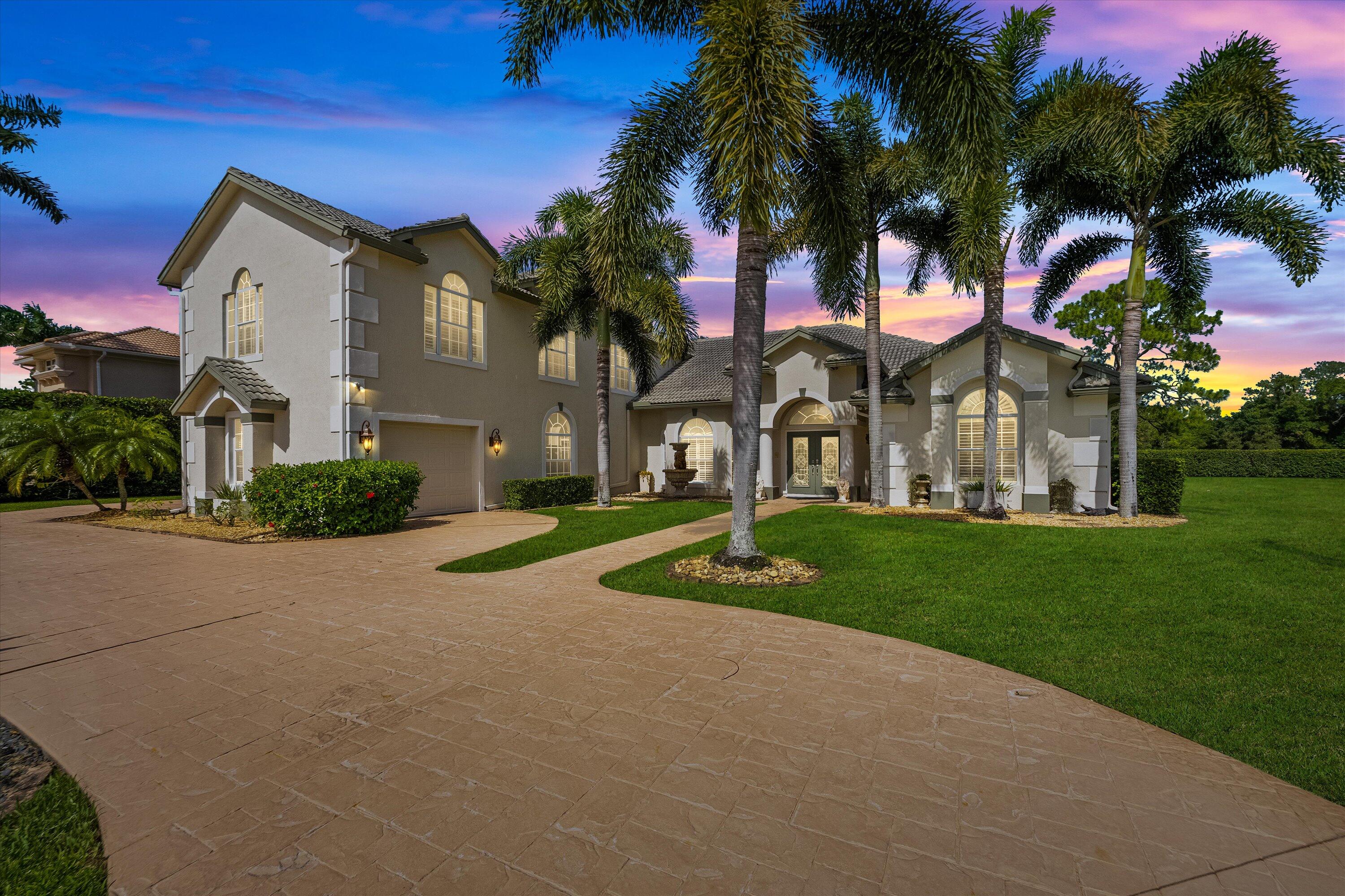 front view of a house with a yard and palm trees