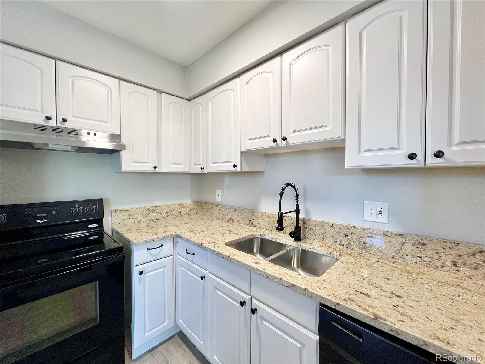 a kitchen with granite countertop a sink stainless steel appliances and white cabinets