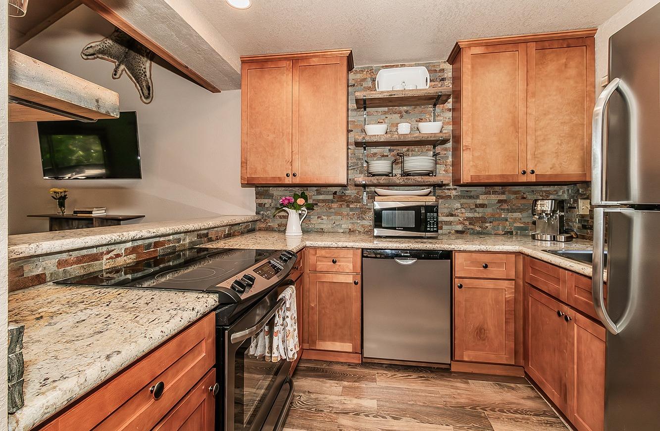 a kitchen with stainless steel appliances granite countertop a stove a sink and a microwave