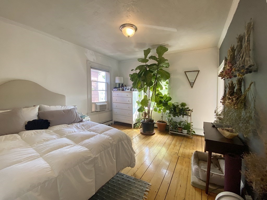 a bedroom with a bed table flowerpot and a potted plant