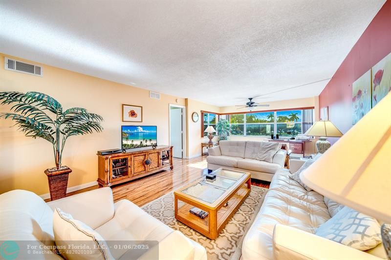 a living room with furniture a large window with kitchen view