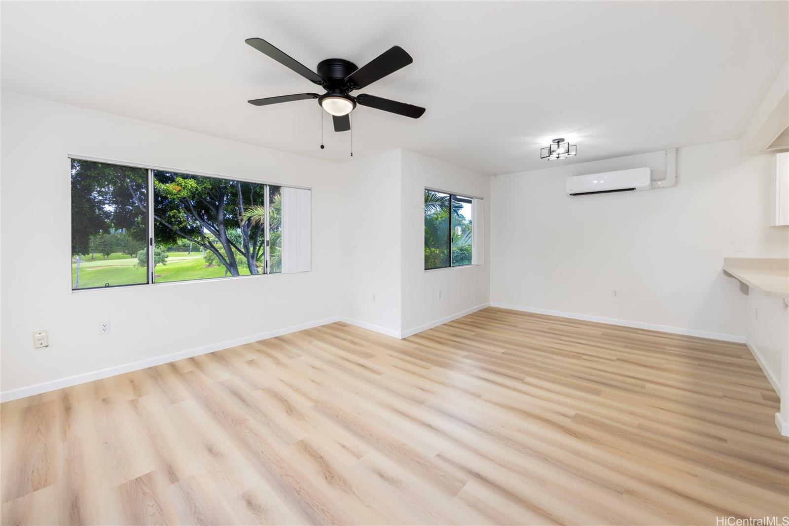 a view of empty room with wooden floor and fan