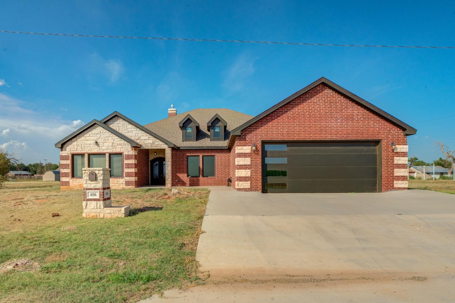 a front view of a house with yard and trees in the background