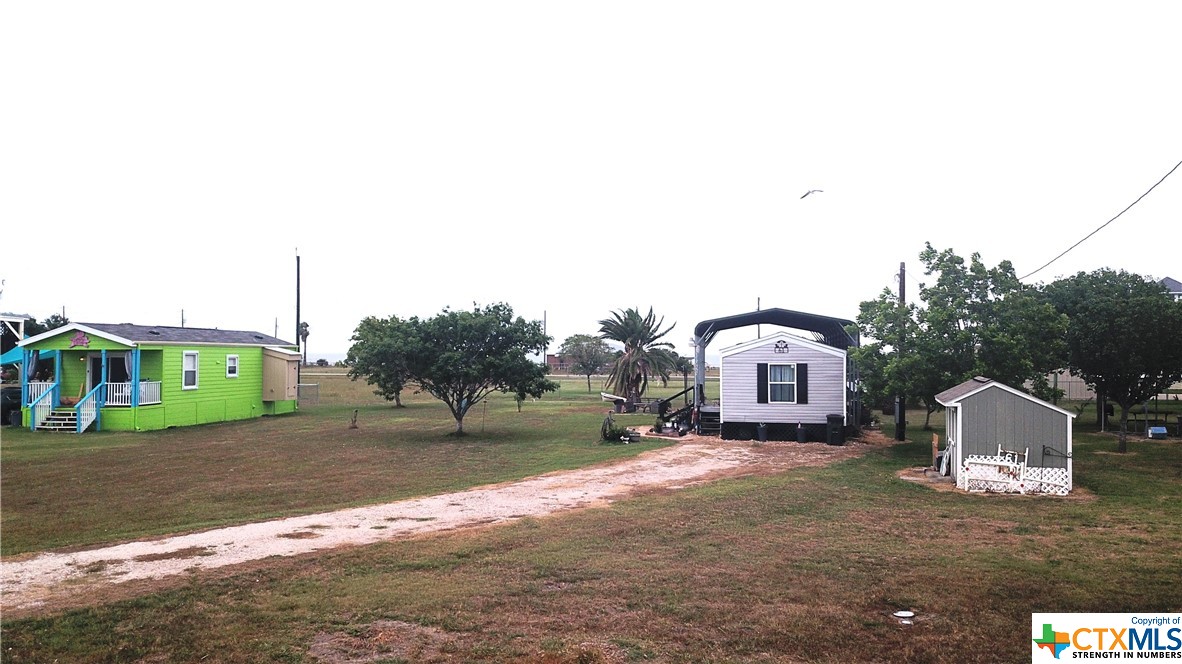 a view of a house with a yard and large trees