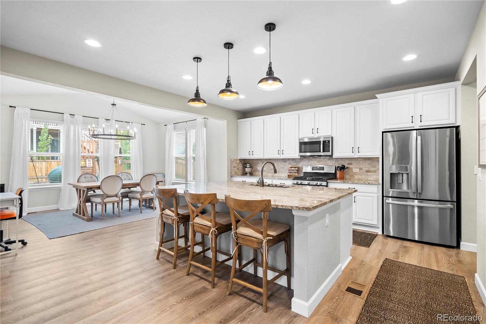 a kitchen with stainless steel appliances a dining table chairs stove refrigerator and cabinets