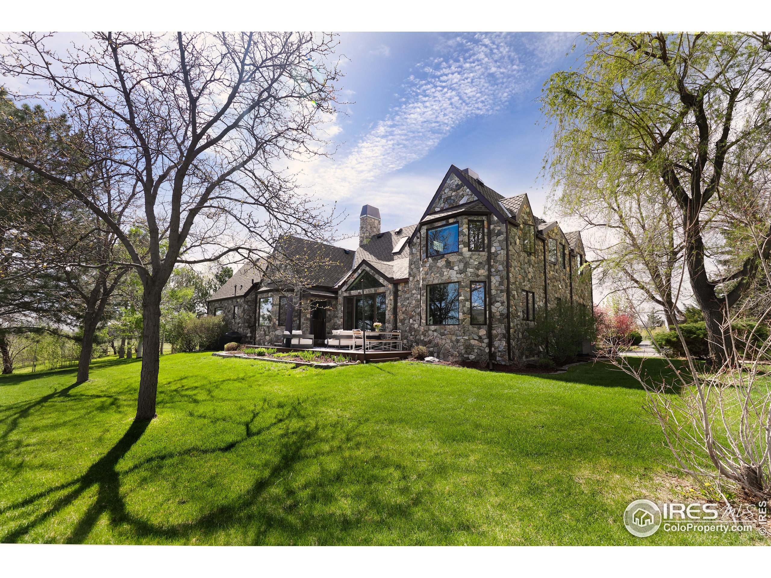 a view of a big house with a big yard and large trees