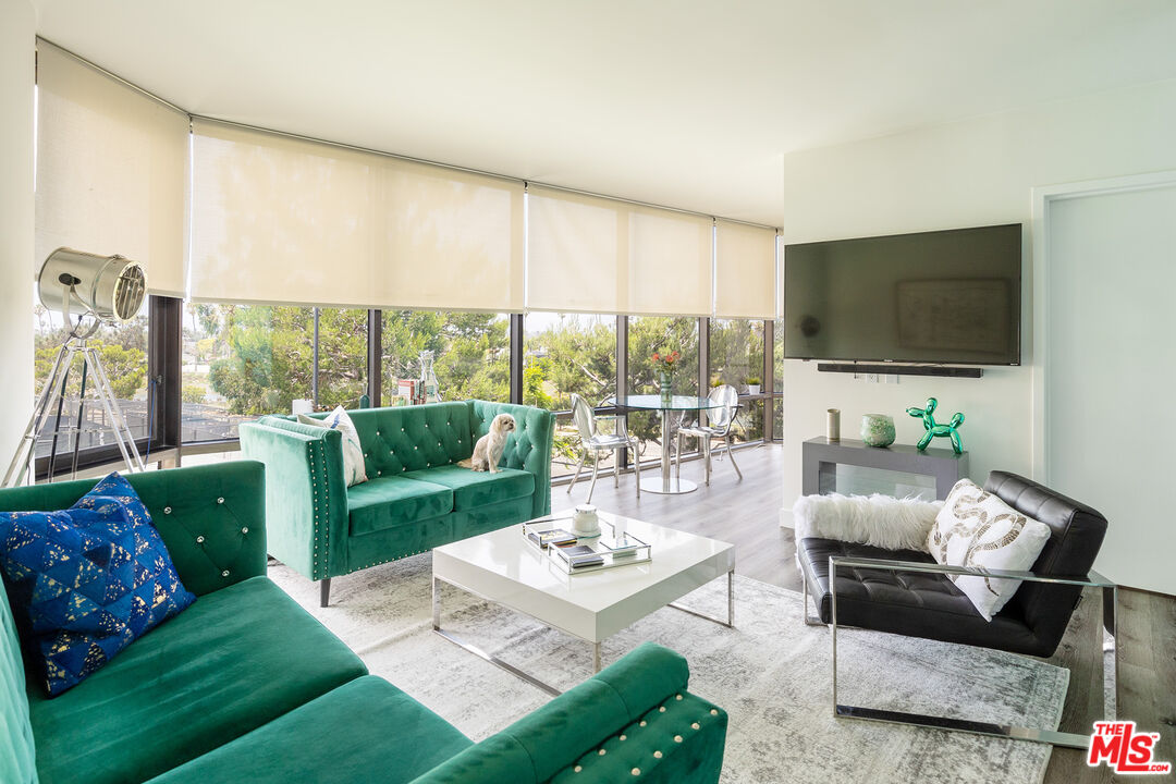 a living room with furniture a flat screen tv and a floor to ceiling window