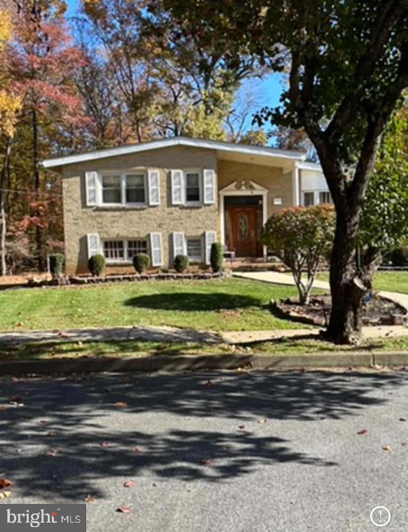 a front view of a house with a garden and trees