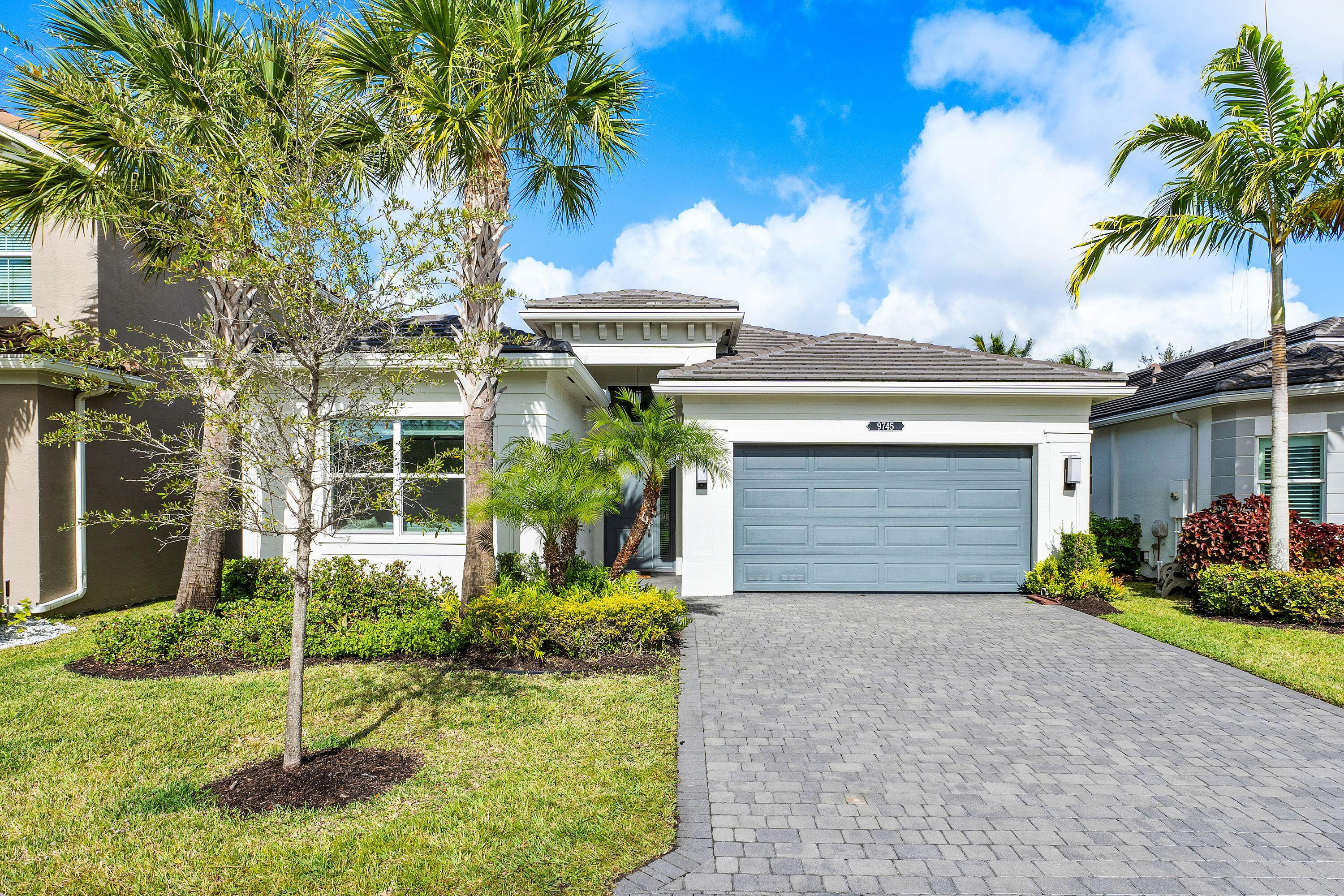 front view of a house with a yard and palm trees