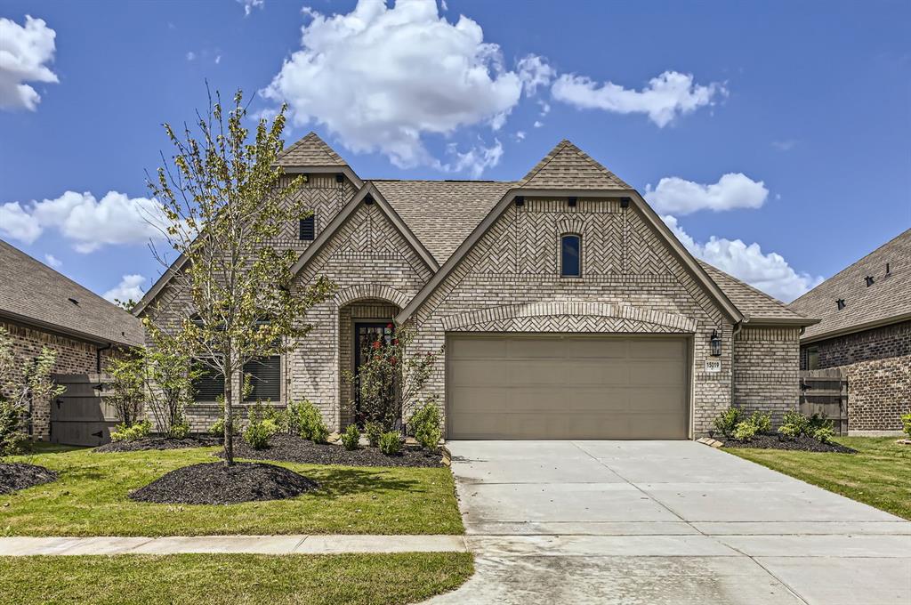 This is a modern single-story brick home featuring a two-car garage, a neatly landscaped front yard, and a welcoming entryway, situated under a clear sky in a suburban neighborhood.