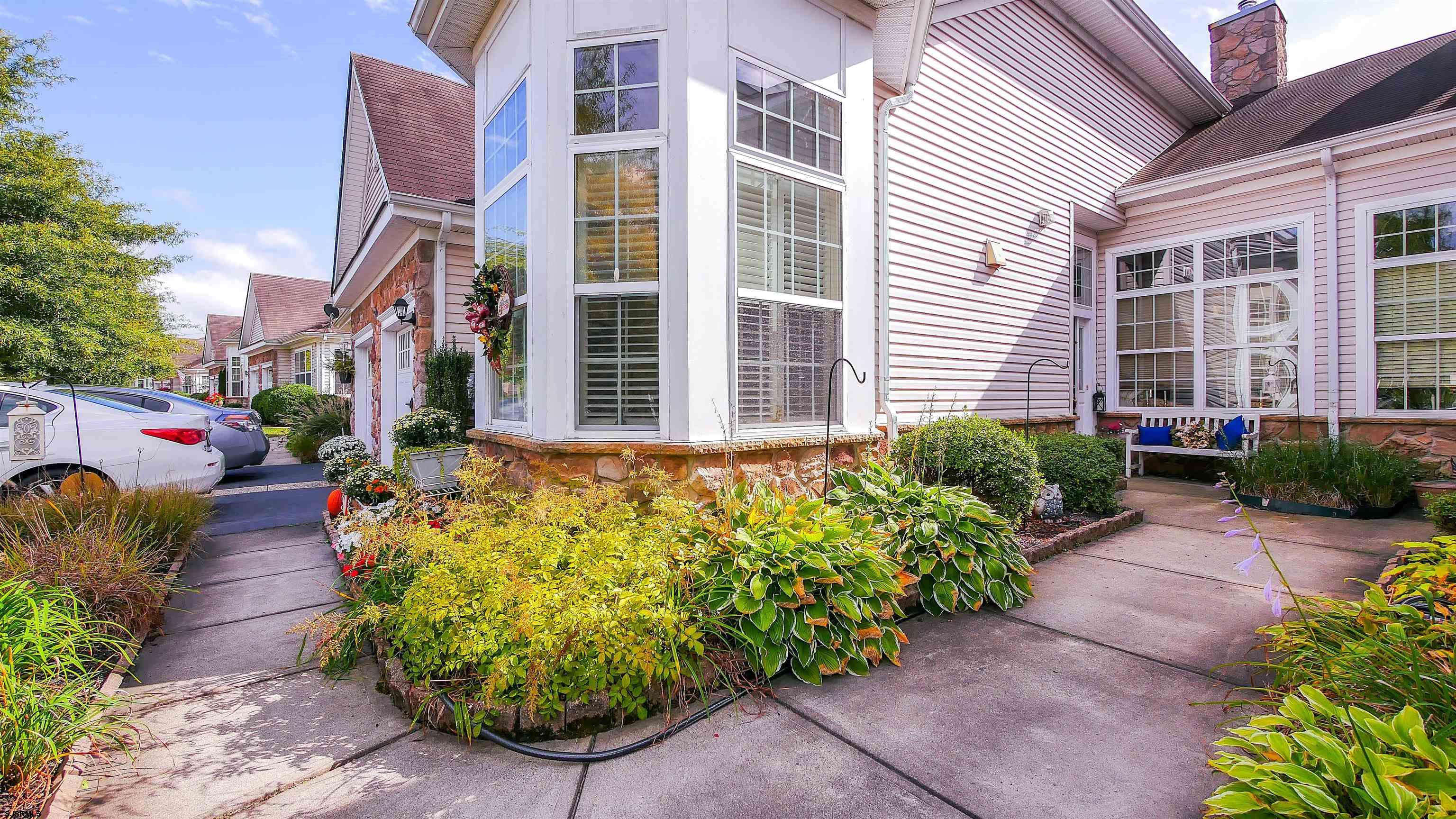 a view of a house with potted plants and a flower garden