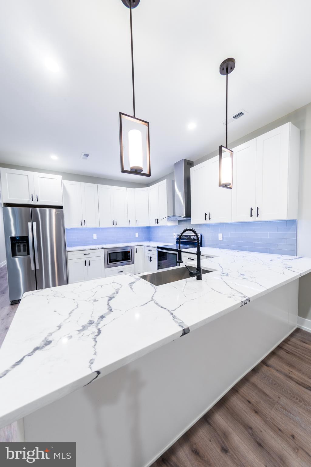 a large kitchen with kitchen island a sink stainless steel appliances and a chandelier