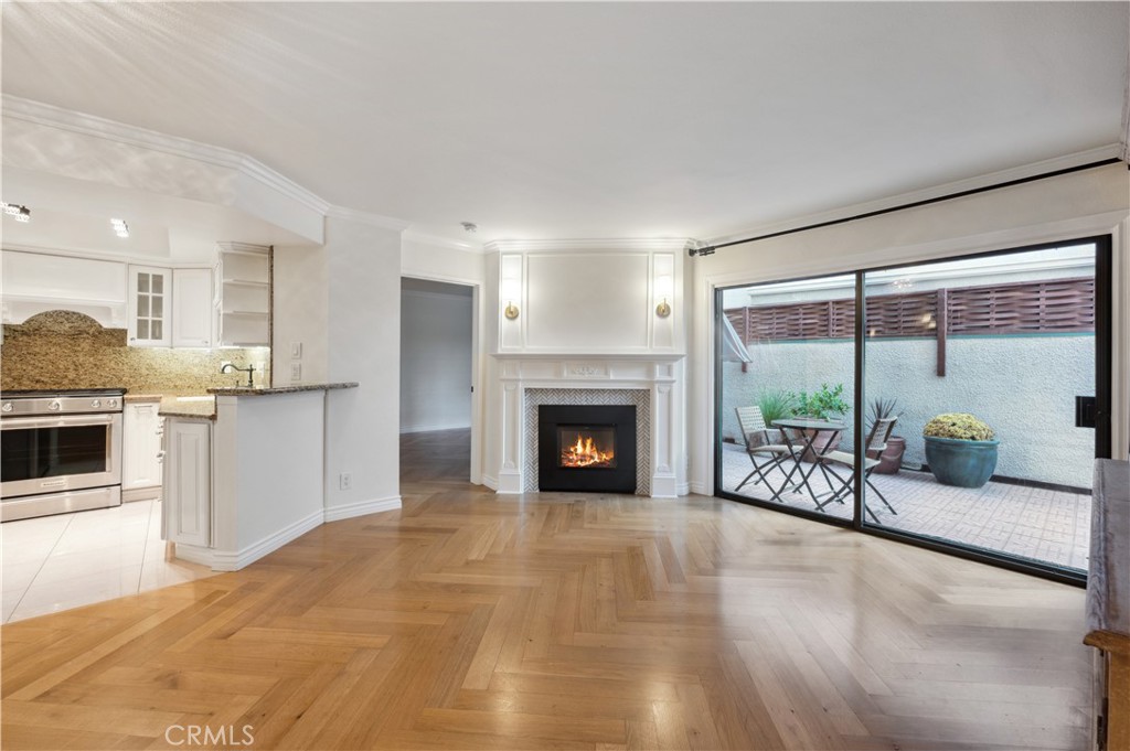 a view of a livingroom with a fireplace a kitchen a sink and a large window