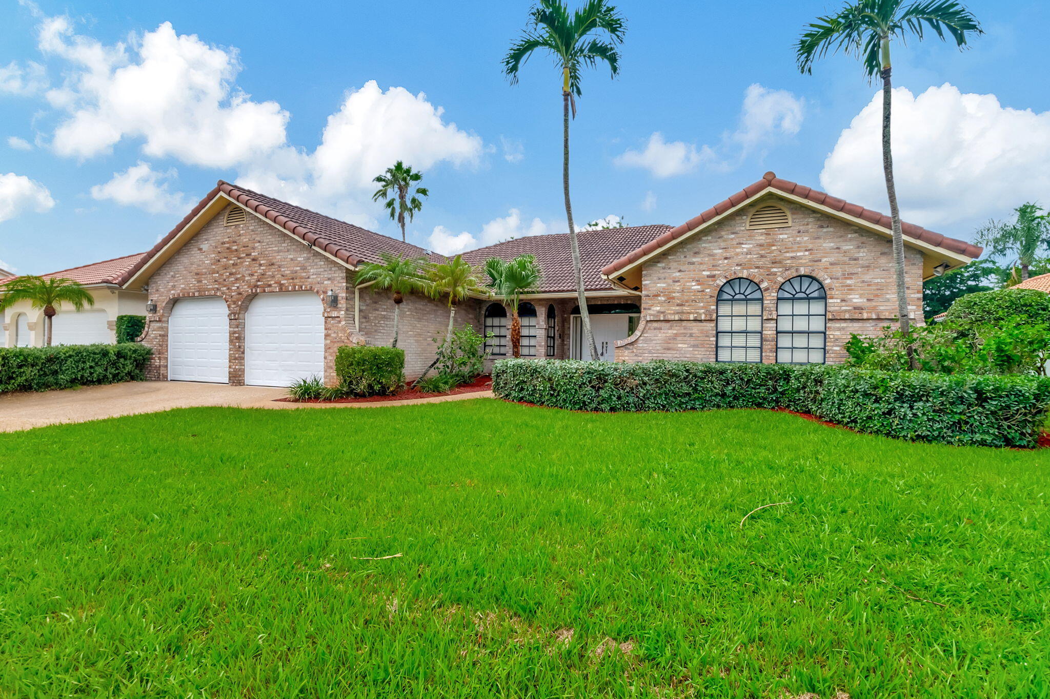 a view of a house next to a yard with palm trees