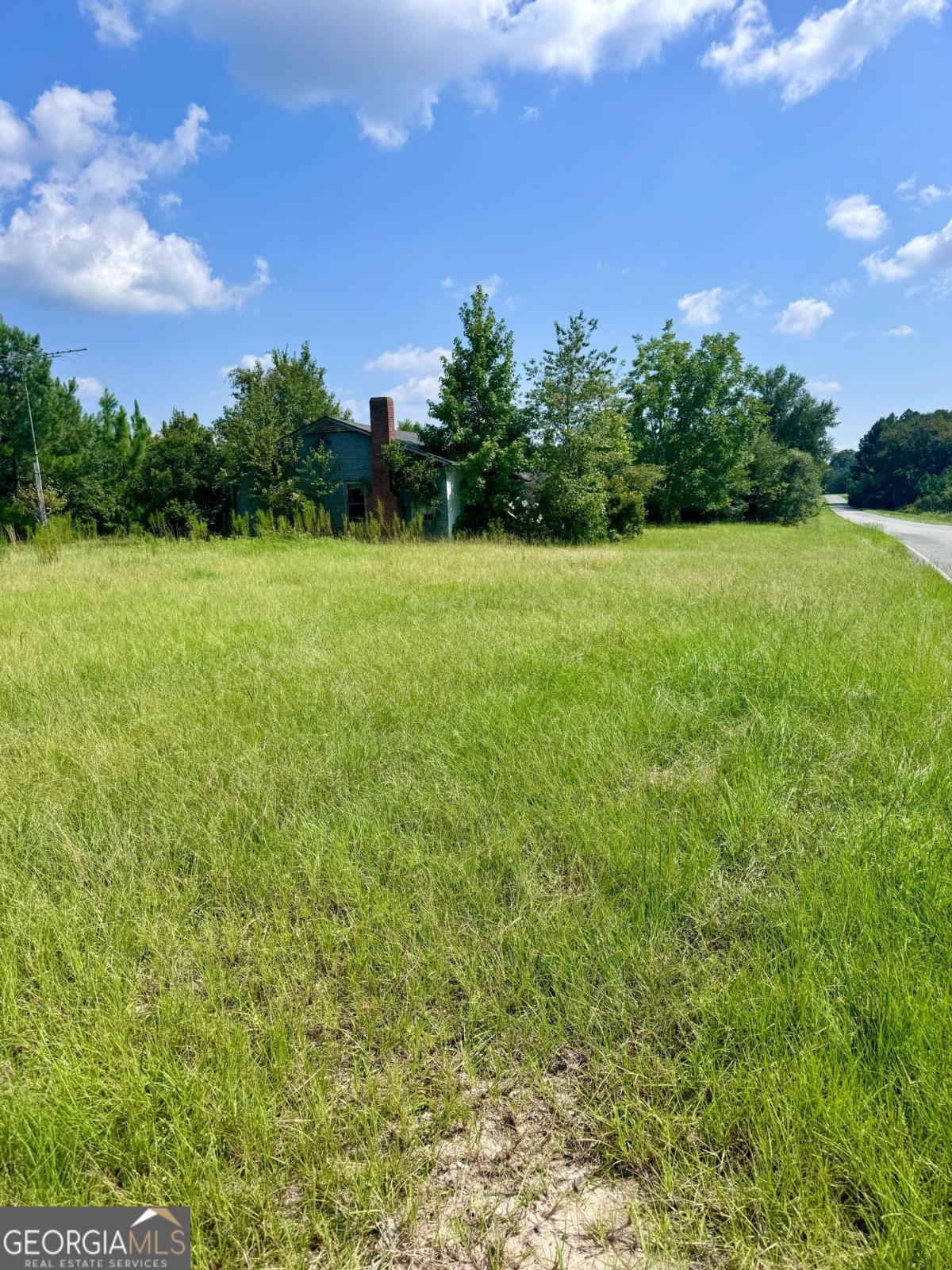 a view of a green field with wooden fence