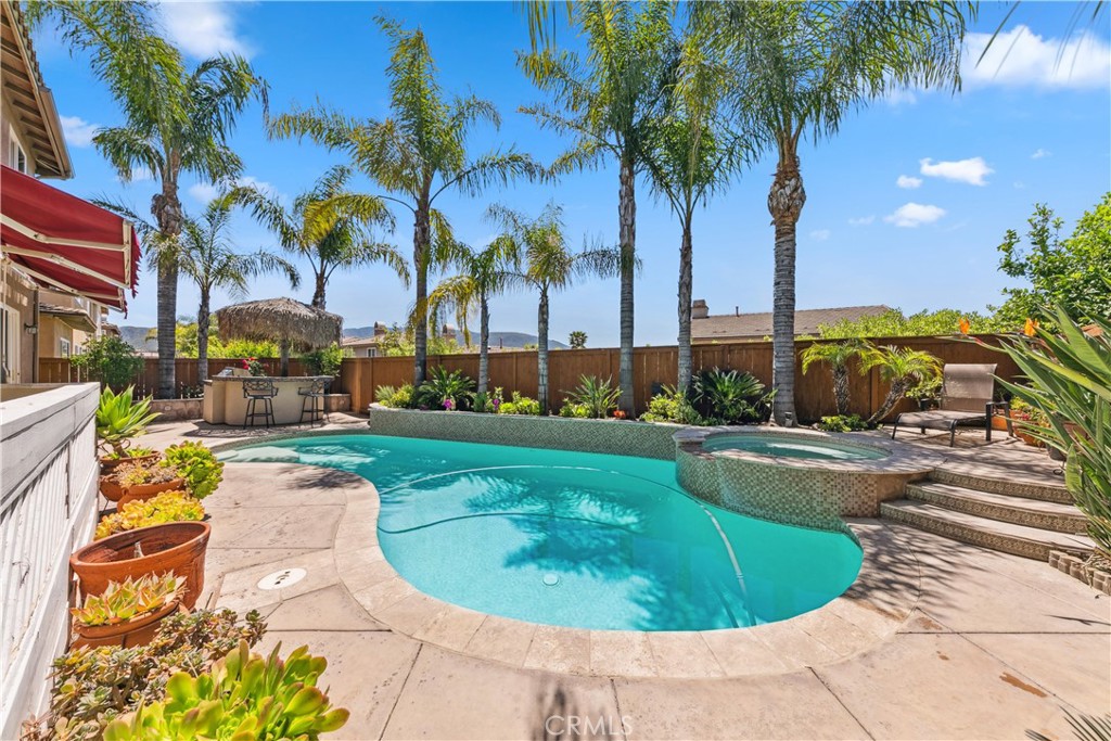 a view of a swimming pool with a lawn chairs and palm trees