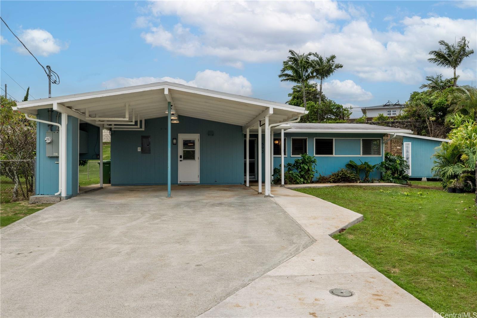 Property from the street shows the driveway with room for multiple cars, carport, two front entrances and spacious front yard.