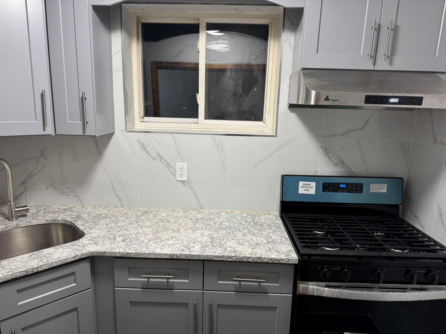 Kitchen featuring gray cabinetry, ventilation hood, sink, tasteful backsplash, and gas stove