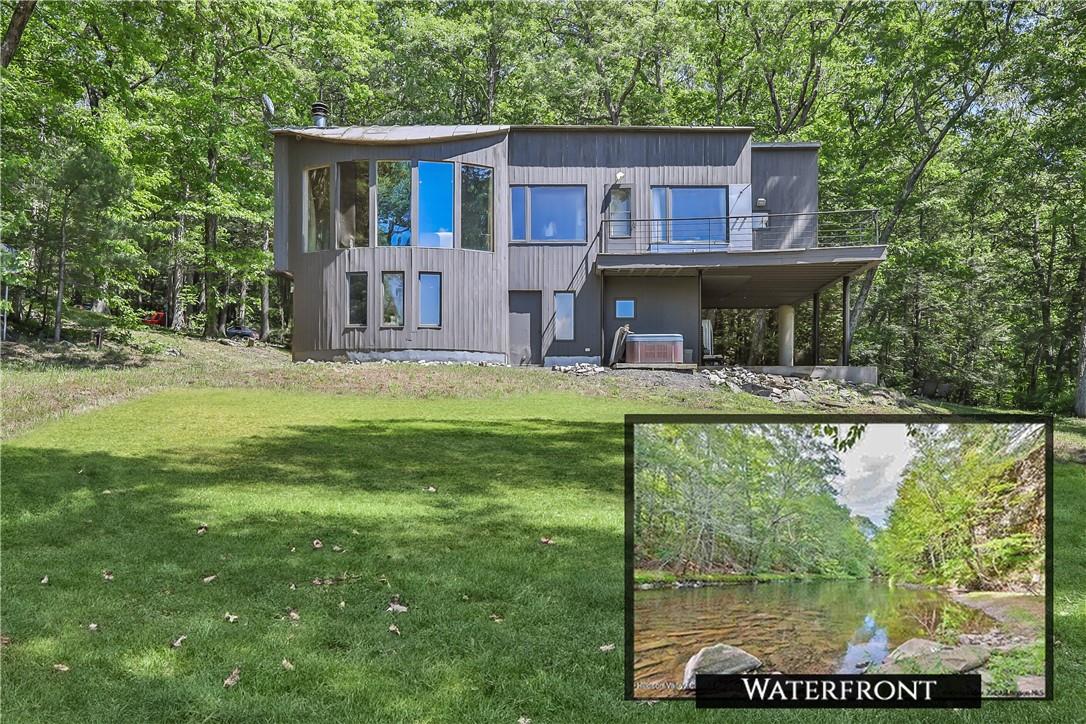 Back of house featuring a yard, a water view, and a balcony