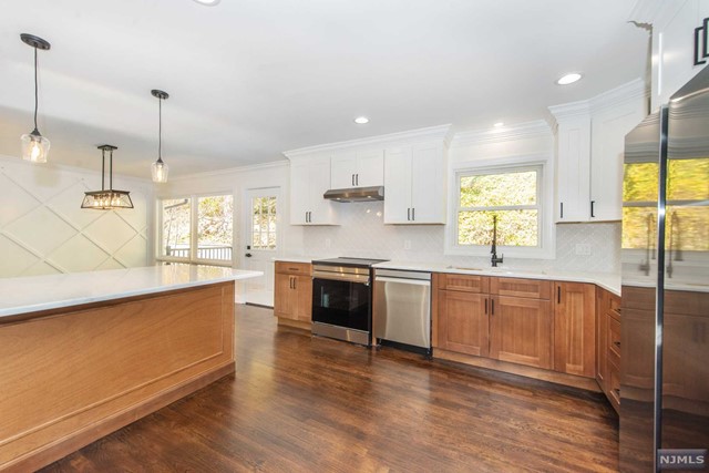 a large kitchen with stainless steel appliances granite countertop a stove a sink and a wooden floors