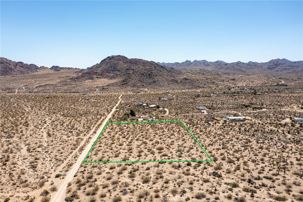 an aerial view of house with yard and mountain view in back