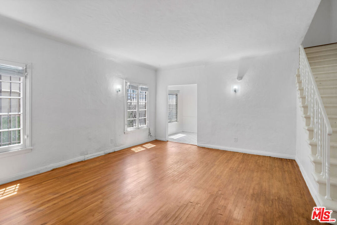 a view of an empty room with wooden floor and a window