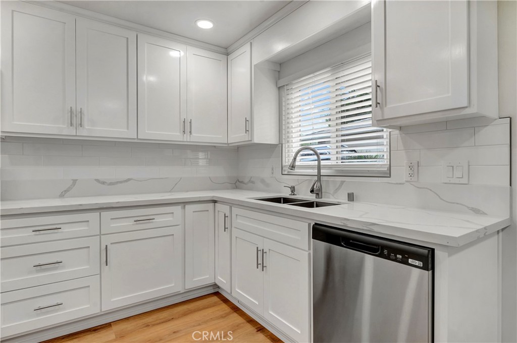 a kitchen with white cabinets appliances a sink and a window