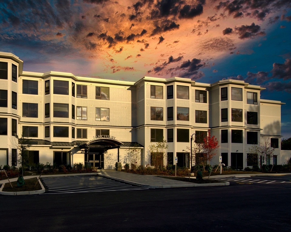 a front view of a building with street view and trees