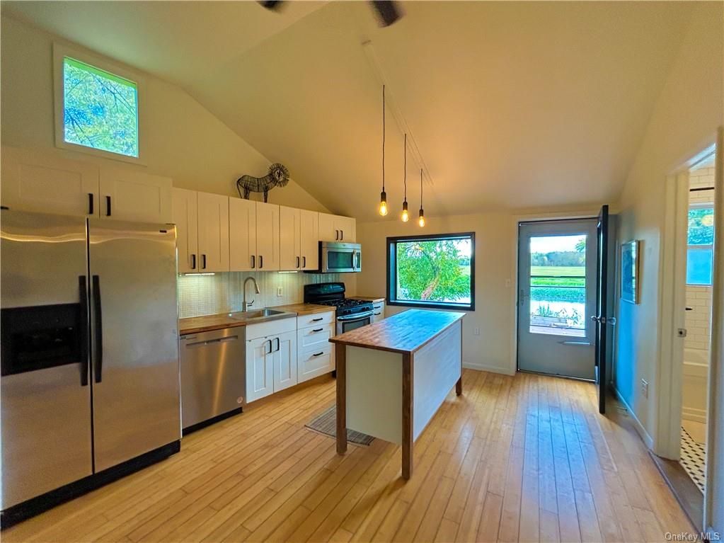 a kitchen with kitchen island wooden floors appliances and cabinets